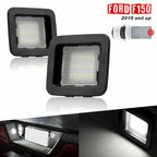 A pair of F150 License plate lights of black housing with clear lens. Two black square LED license plate light bulbs for Ford F150 2015 and up, shown on a white background with a small diagram and illuminated inset photos demonstrating use.