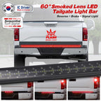 A 60-inch smoked lens LED tailgate light bar shown installed on the rear bumper of a white pickup truck, with text overlays indicating sequential turn signal and brake light functionality. The image includes a close-up of the light bar and three smaller demonstration panels at the bottom showing the light bars in use.