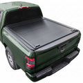 A black roll-up truck bed cover installed on the bed of a dark green pickup truck, shown from a rear three-quarter angle against a plain white background.