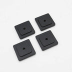 Four black square rubber washers on a white background