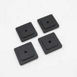 Four black square rubber washers on a white background
