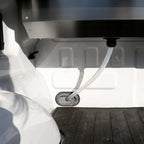 Close-up of a white hose connected to a metal valve on a vehicle's undercarriage.