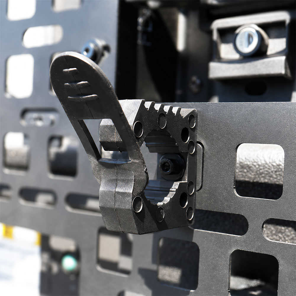 Close-up of a black metal mounting bracket attached to a perforated metal panel, with a lock secured on the right side.