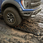 Trucks with off-road tire stuck in mud, using recovery tracks for traction