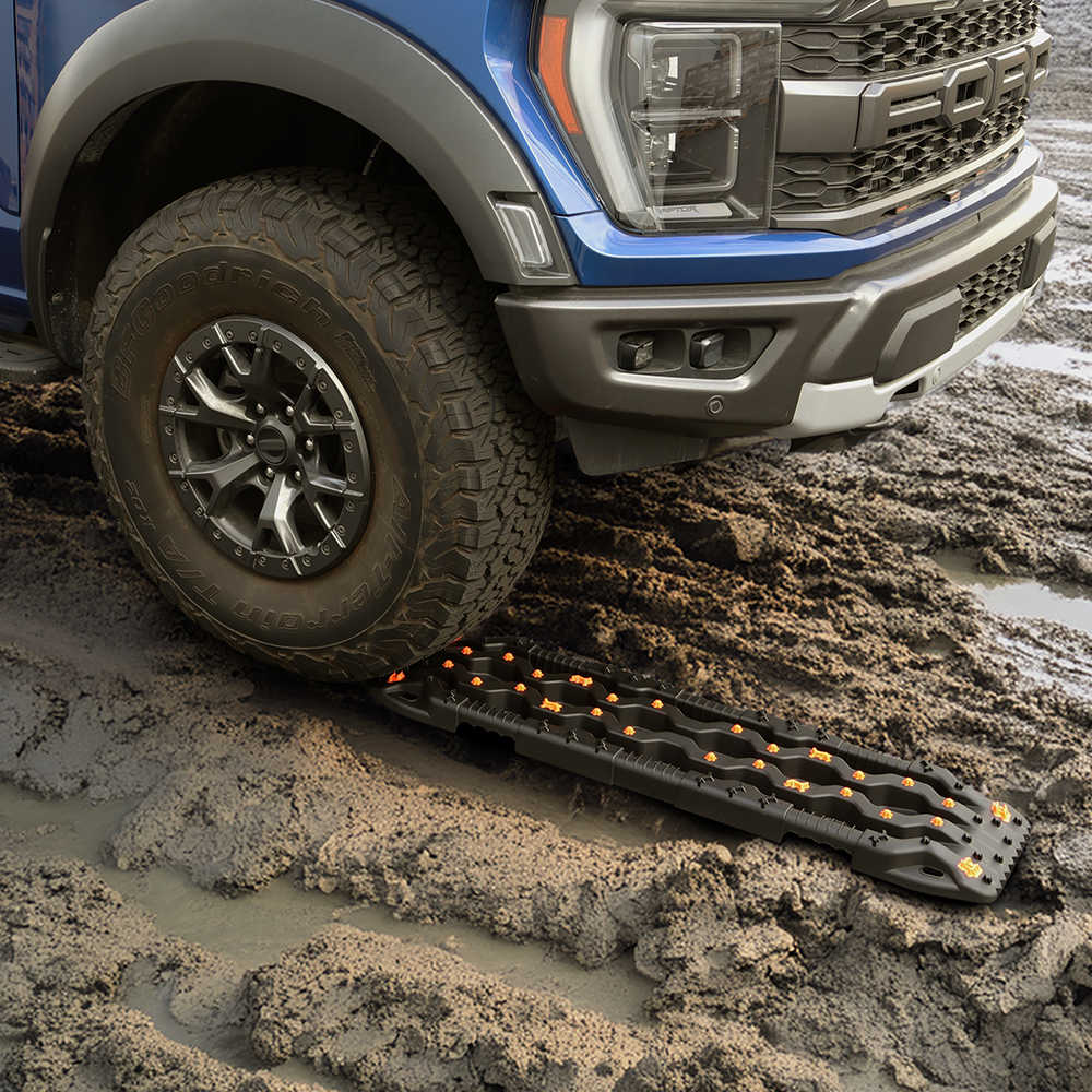 Trucks with off-road tire stuck in mud, using recovery tracks for traction