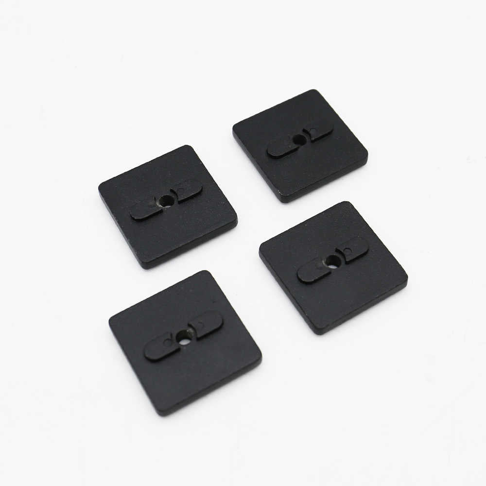 Four black square buttons with central holes on a white background