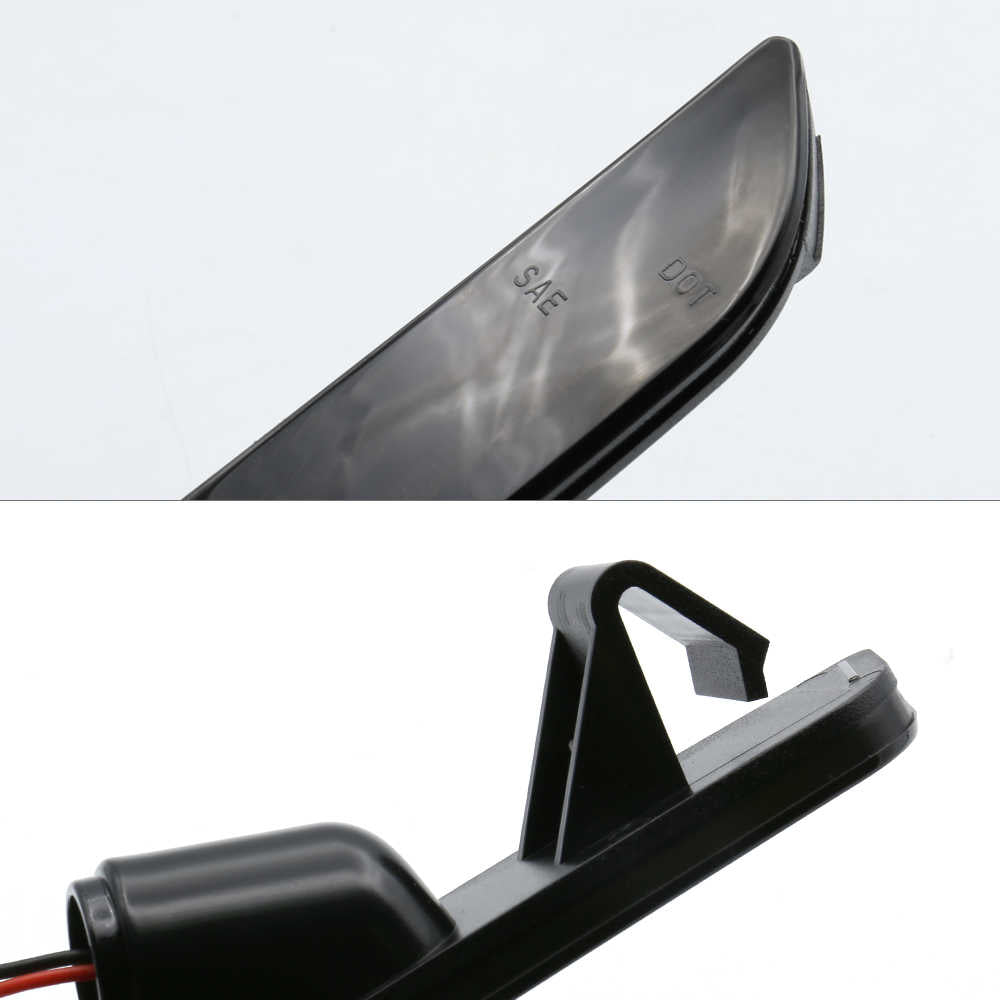 Close-up of a black plastic automotive light assembly, showing the lens edge marked SAE and DOT, and the mounting bracket and wiring connector against a white background.