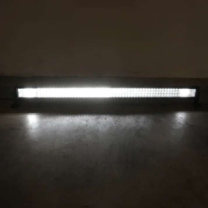 A long rectangular LED light bar mounted low on a dark wall above a concrete floor, casting a bright white glow downward.