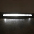 A long rectangular LED light bar mounted low on a dark wall above a concrete floor, casting a bright white glow downward.