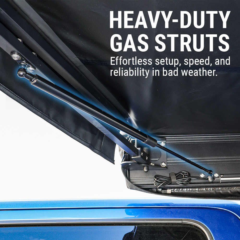 Close-up of a black hardtop tent canopy attached to a blue vehicle, showing a heavy-duty gas strut support arm with overlaid marketing text reading 'HEAVY-DUTY GAS STRUTS' and supporting copy.