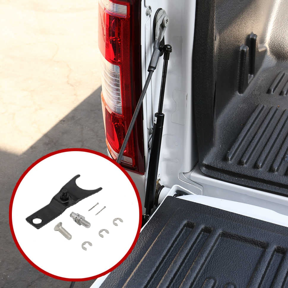 A black metal hitch receiver bracket with mounting hardware shown in a circular inset, installed beside a vehicle tailgate and bed. The photo is taken outdoors near a white truck bed with a black textured liner.