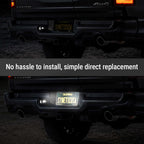 A rear view of a black truck showing a license plate light installed on the left side of the bumper, with a text overlay that reads 'No hassle to install, simple direct replacement'.