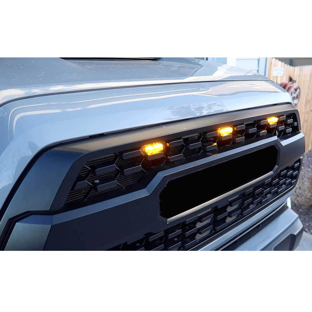 Close-up of a car's front grille with illuminated indicator lights.