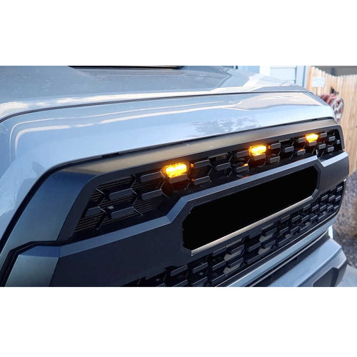 Close-up of a car's front grille with illuminated indicator lights.