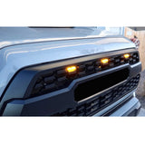 Close-up of a car's front grille with illuminated indicator lights.