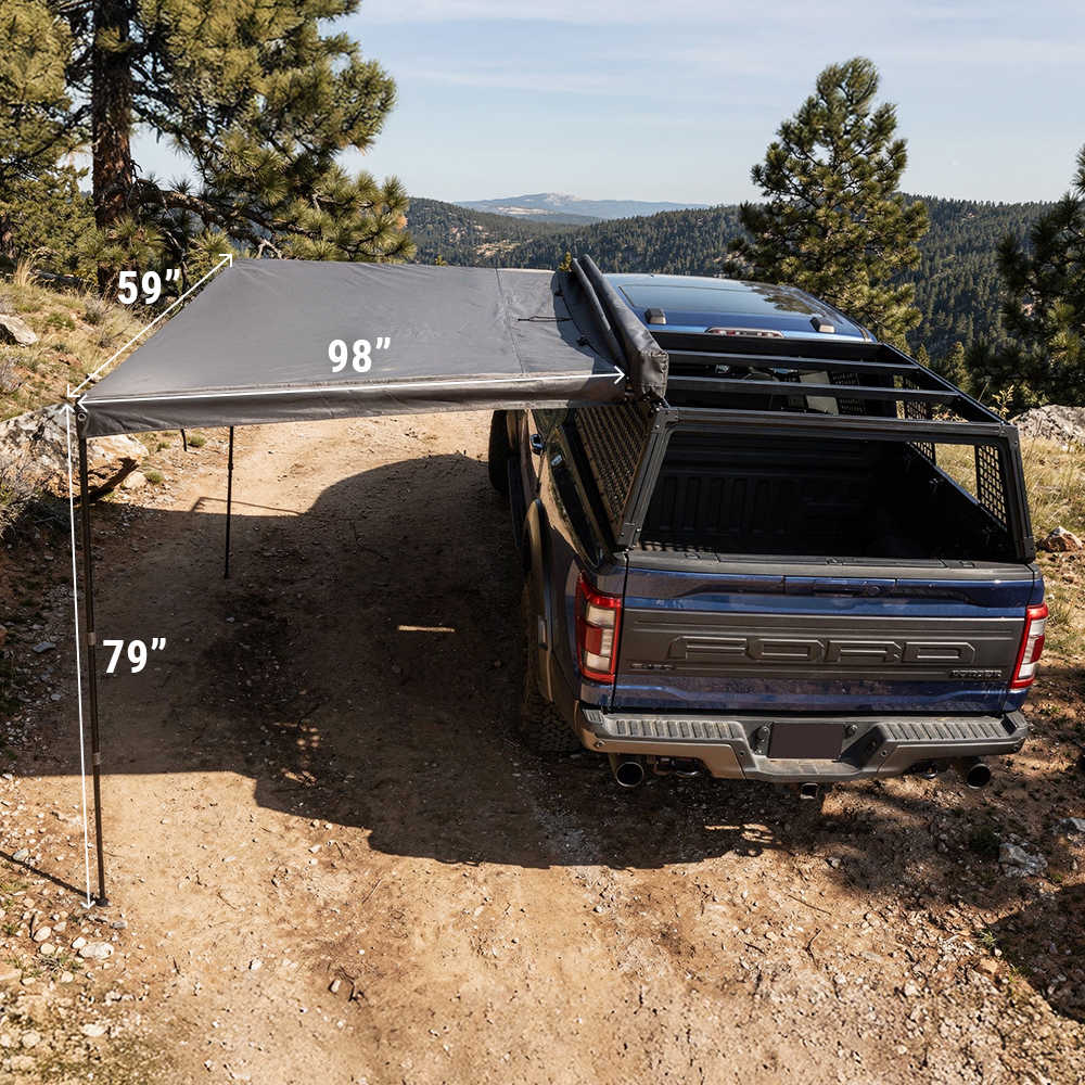 Blue truck with a gray rooftop tent in a natural setting with trees and mountains.