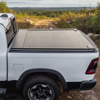 White truck with a tonneau cover on a dirt road in a natural landscape