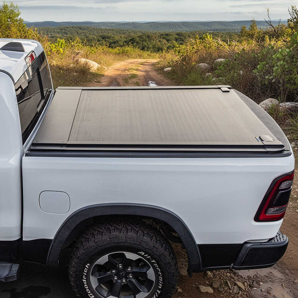 White truck with a tonneau cover on a dirt road in a natural landscape