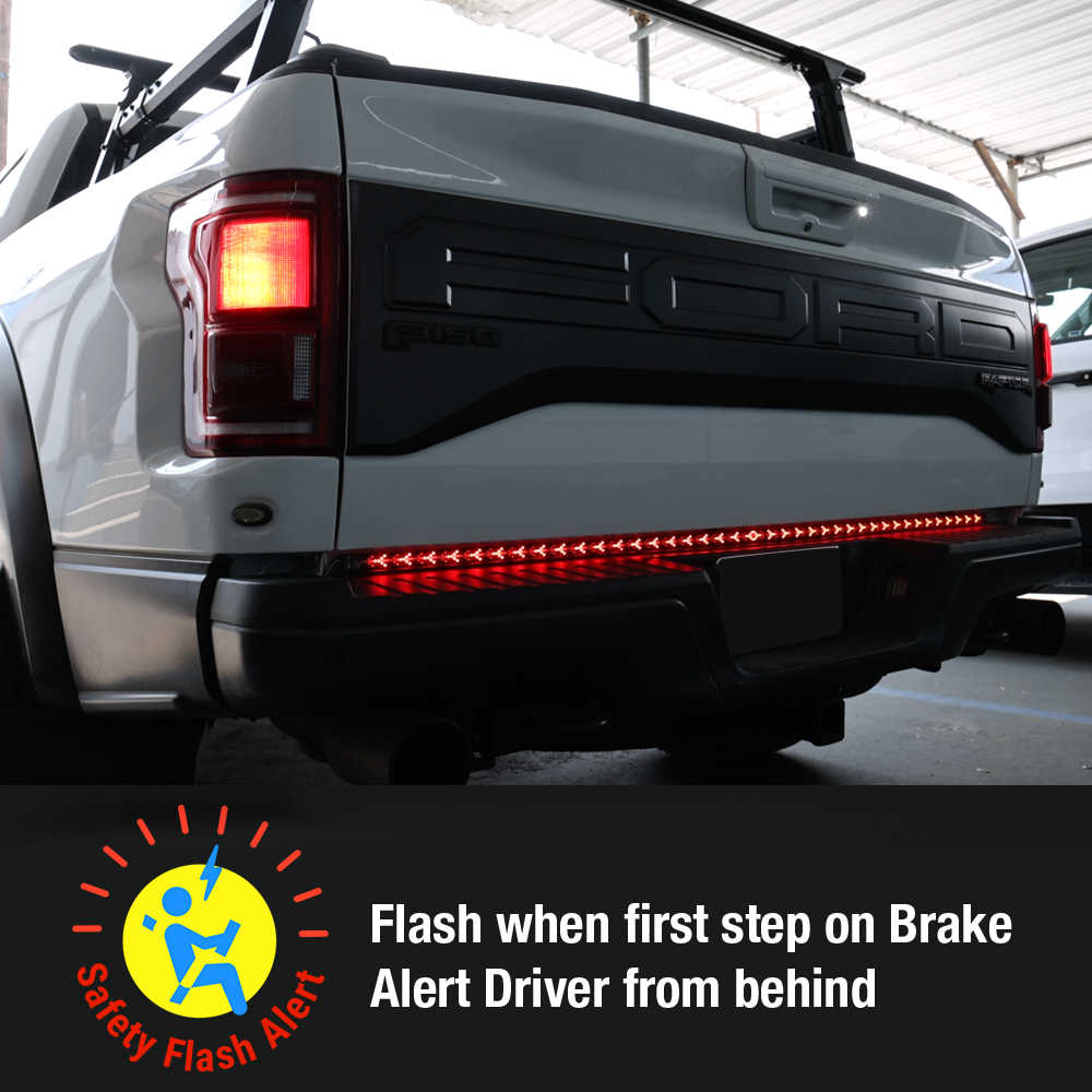 Rear view of a white pickup truck with a red LED safety flash bar illuminated across the bumper, plus a text overlay explaining the safety function.