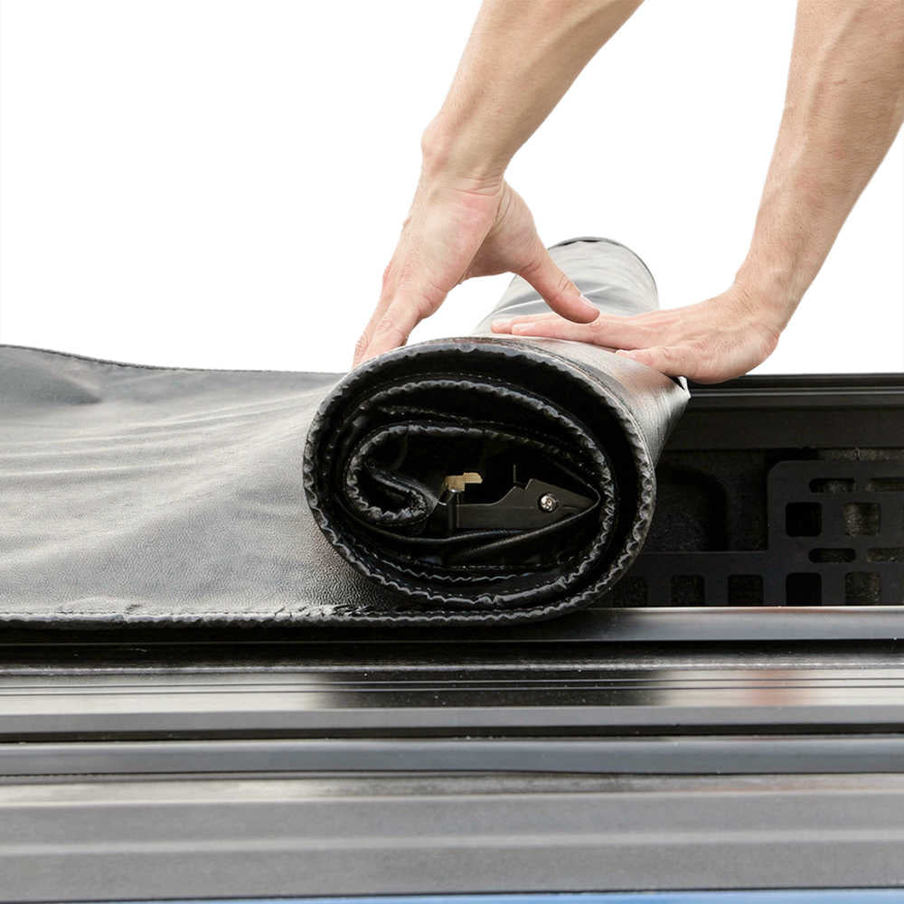Person unrolling a black and gray mat or rug onto a surface.