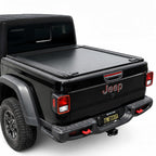 A black tonneau cover installed on the bed of a black Jeep Gladiator, shown from a rear three-quarter angle against a white studio background.