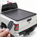 A white Nissan Frontier truck featuring a retractable tonneau cover, shown being operated by a remote held in a hand.
