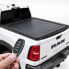 Retractable tonneau cover installed on the bed of a white RAM truck, operated by a key fob remote.