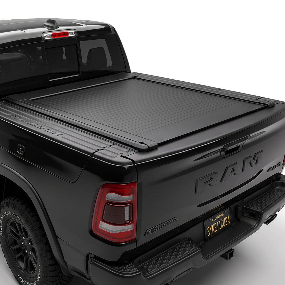 A black tonneau cover installed on the bed of a black Ram pickup truck.
