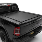 A black tonneau cover installed on the bed of a black Ram pickup truck.
