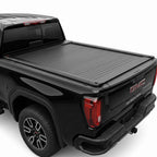 A black truck bed cover installed on the bed of a black GMC Sierra pickup truck.
 