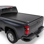A black retractable truck bed cover installed on the bed of a dark gray Chevrolet Silverado.