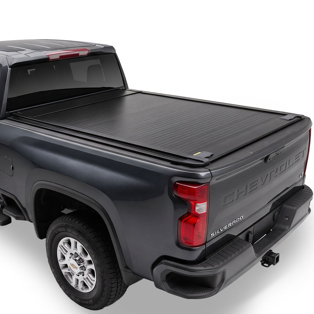 A black retractable truck bed cover installed on the bed of a dark gray Chevrolet Silverado.