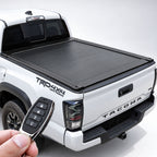 White Toyota Tacoma with closed black retractable tonneau cover, with a remote fob held in the foreground.