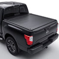 A black truck bed cover installed on the bed of a black Nissan Titan pickup truck.
