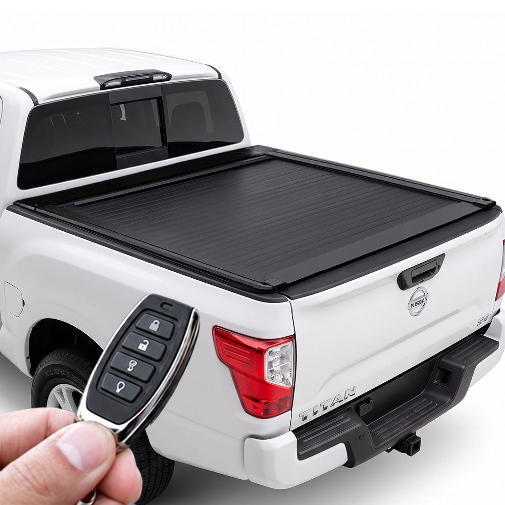 A black roll-up truck bed cover installed on the bed of a white pickup truck, shown with a hand holding a key fob in the foreground against a clean white background.
