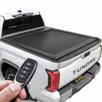 A white Toyota Tundra pickup truck. A hand holds a four-button black key fob remote