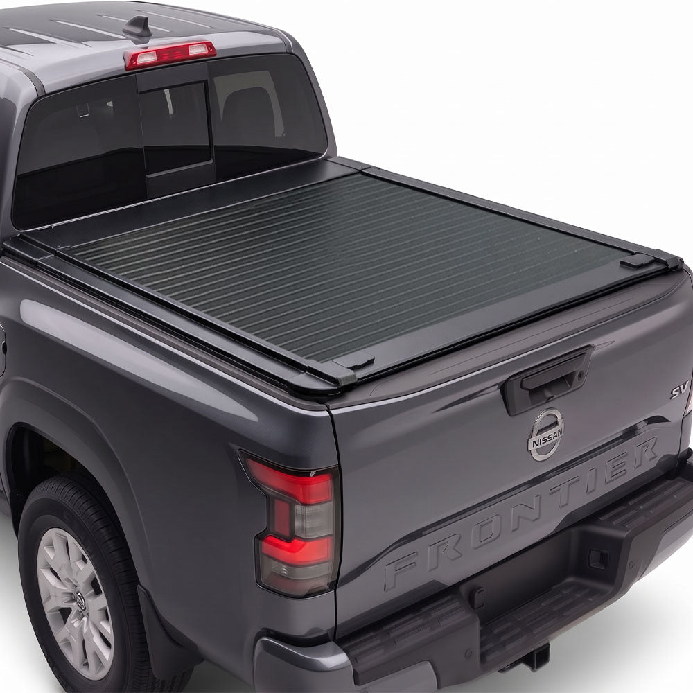 A retractable truck bed cover installed on the bed of a dark gray Nissan Frontier pickup truck.
