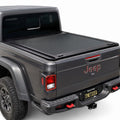 A retractable truck bed cover installed on the bed of a dark gray Jeep.