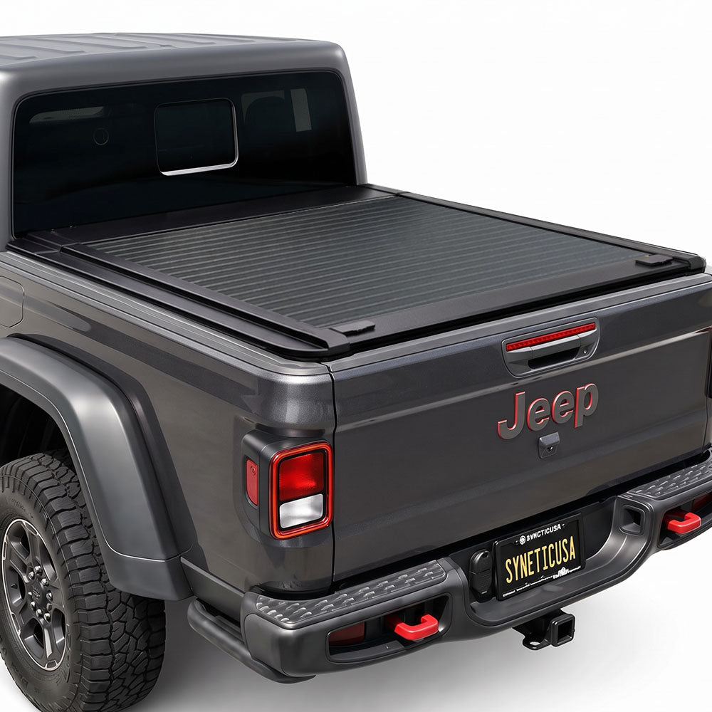 A retractable truck bed cover installed on the bed of a dark gray Jeep.