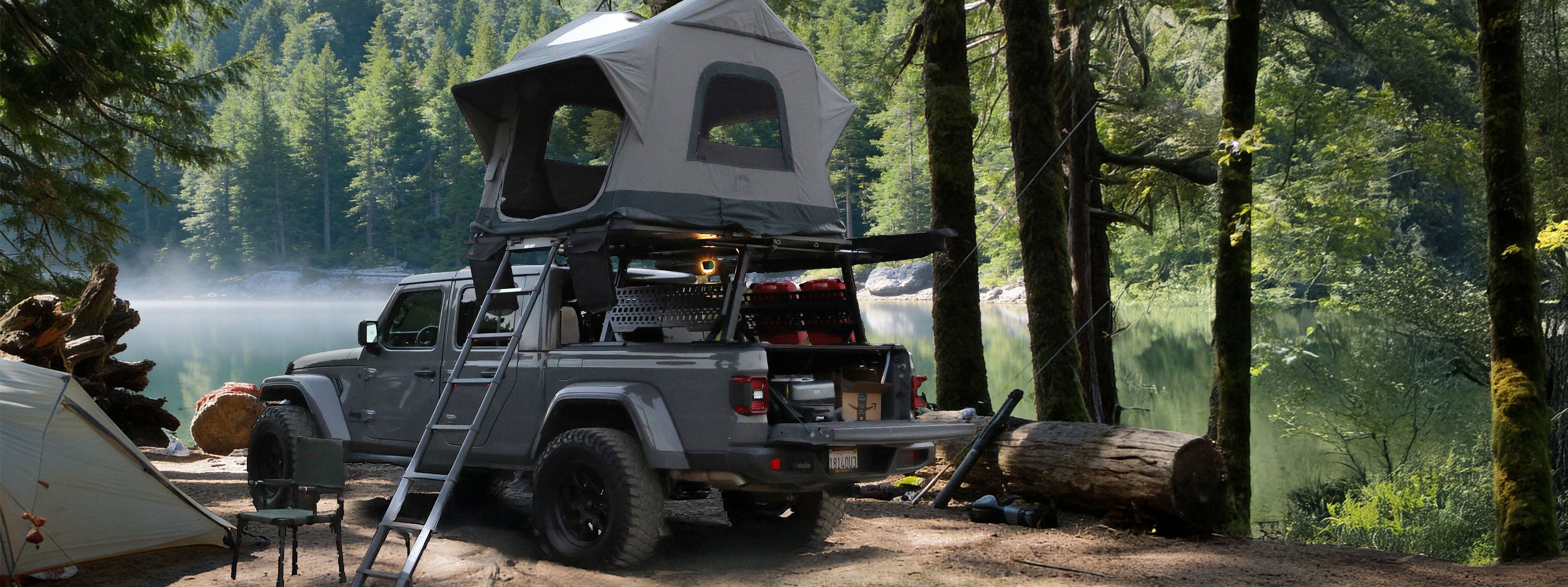 Roof top tent on a truck in a forest setting with a lake in the background