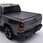 A black retractable truck bed cover installed on the bed of a dark gray Ram pickup truck.