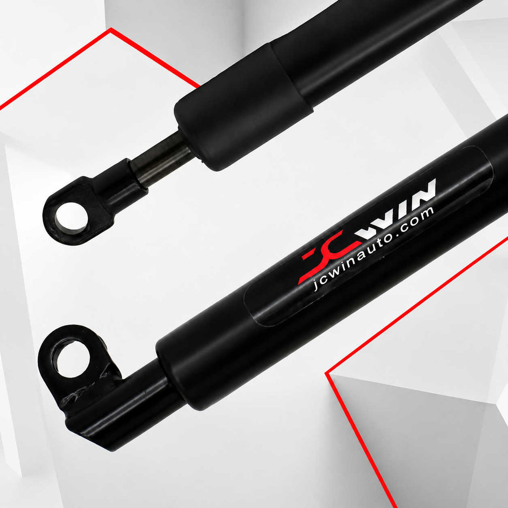 Two black hydraulic power steering reservoirs with metal mounting rings, shown on a white geometric background with red graphic lines. The lower reservoir features a printed logo and website 'JCWIN jcwinauto.com.