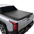A black soft roll-up tonneau cover installed on the bed of a silver pickup truck